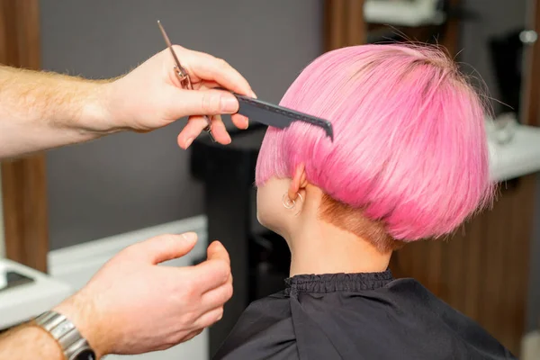 理发师的手在美容院里为一位年轻的高加索女人梳头 做短粉色的发型 — 图库照片