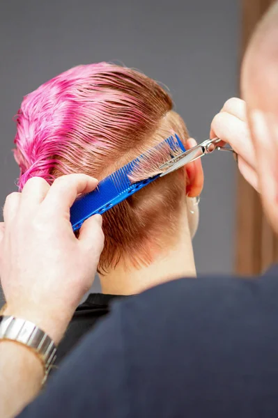 有新发型的女人男发型师用剪子在发廊里剪粉色短发 — 图库照片