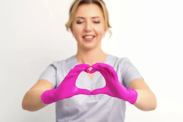 Usmívající Běloška Doktor Růžových Rukavicích Uniformě Zobrazující Symbol Srdce Bílém — Stock fotografie