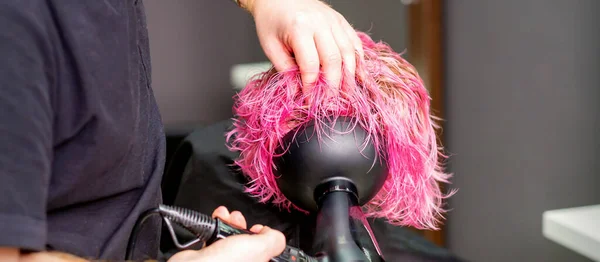 在美容院里 发型师用吹风机吹制湿透的定制粉色头发的发式 — 图库照片