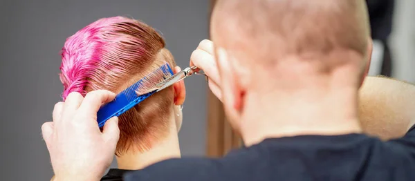 新しい髪型の女性 ヘアサロンではさみでピンクの短い髪を切断男性美容師 — ストック写真