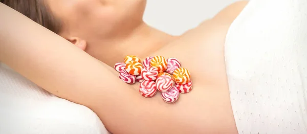 Colored round candies under the female armpit, close up, depilation armpit concept