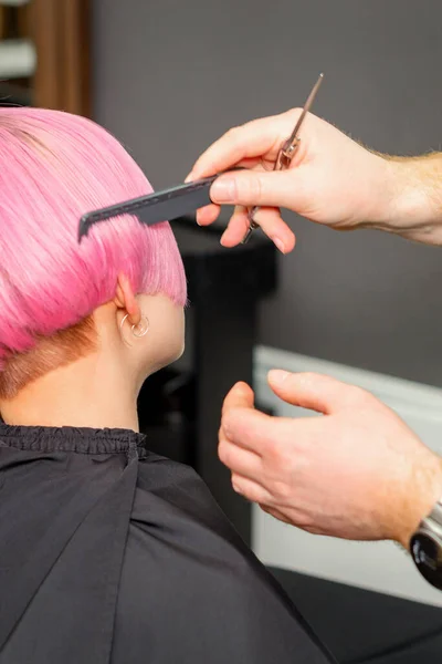 美容室で若い白人女性のための短いピンクのヘアスタイルを作る髪を組み合わせた美容師の手 — ストック写真