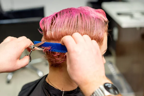 美容室で櫛を持って来る若い白人女性の髪の毛を染めぬれたピンクの短い髪をカット — ストック写真