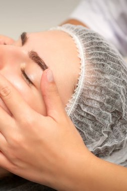 Kaplıca salonundaki güzel bayan hasta için yüz masajı.