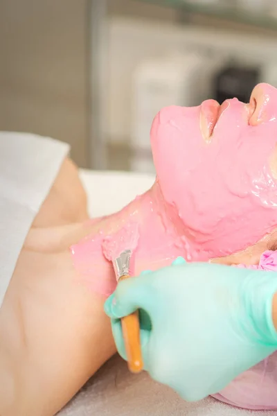 Hand Van Cosmetoloog Het Aanbrengen Van Roze Alginemasker Met Borstel — Stockfoto