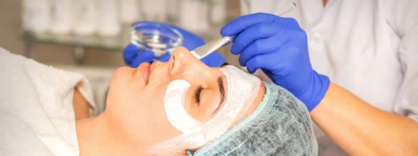 美容師に顔の剥離 顔の治療 美容師は女性患者にクレンジングフェイスマスクを適用します — ストック写真