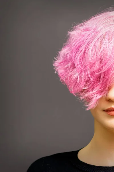 Stock image Beautiful young caucasian woman with short curly bob hairstyle dyed in pink color with closed eyes against dark gray background with copy space