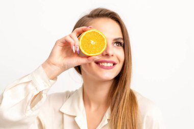 Beyaz arka planda beyaz gömlek giyen, turuncu bir kesikle gözünü kapatan neşeli beyaz bir kadının portresi.