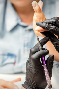 Manikür boyama sanatı. Manikür ustası tırnak ucuna ince bir fırçayla resim çiziyor.