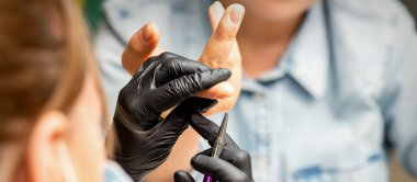 Manikür boyama sanatı. Manikür ustası tırnak ucuna ince bir fırçayla resim çiziyor.