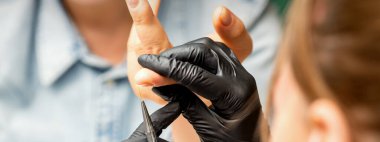 Manikür boyama sanatı. Manikür ustası tırnak ucuna ince bir fırçayla resim çiziyor.