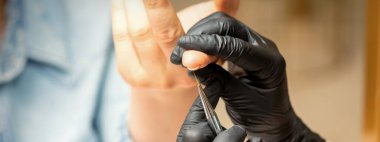 Manikür boyama sanatı. Manikür ustası tırnak ucuna ince bir fırçayla resim çiziyor.