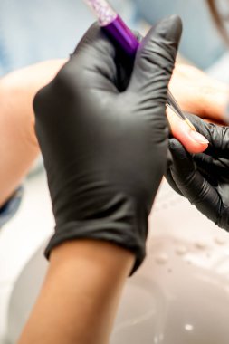 Manikür boyama sanatı. Manikür ustası tırnak ucuna ince bir fırçayla resim çiziyor.