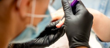 Manikür boyama sanatı. Manikür ustası tırnak ucuna ince bir fırçayla resim çiziyor.