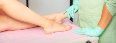 Eldivenli bir kadın podiyatrist hastanedeki kadın ayağı muayene ediyor.