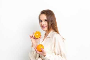 Beyaz arka planda turuncu dilimleri olan beyaz, gülümseyen genç bir kadın.