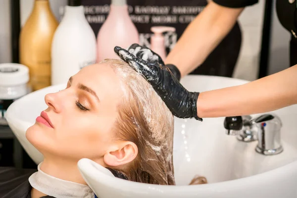 Młoda Kaukaska Kobieta Zamkniętymi Oczami Myje Włosy Przez Profesjonalnego Fryzjera — Zdjęcie stockowe