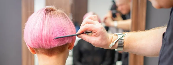 美容室 女性の髪 バックビュー コピースペース バックビューで櫛と若い女性のプロの美容師ブラッシング短いピンクの髪 — ストック写真