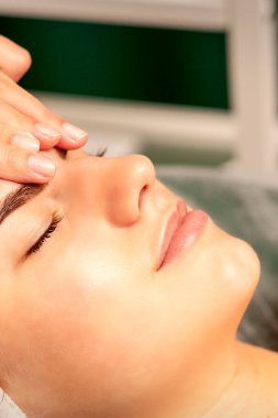 Kafa masajı. Kafkasyalı beyaz güzel bir kadın kaplıca salonundaki kapalı gözlerle kafa ve alın masajı yaptırıyor.