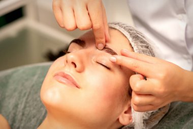 Kaş masajı. Güzel beyaz kadın, spa salonunda gözleri kapalı, göz ve kaş masajı yaptırıyor.