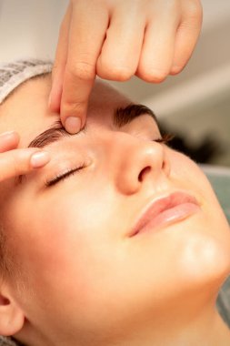 Kaş masajı. Güzel beyaz kadın, spa salonunda gözleri kapalı, göz ve kaş masajı yaptırıyor.