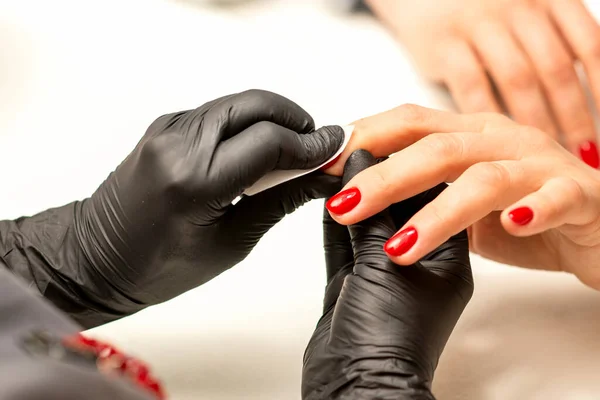 美容师用棉布餐巾 抹布在美容院里擦拭并擦拭完红指甲的过程 然后关门 — 图库照片