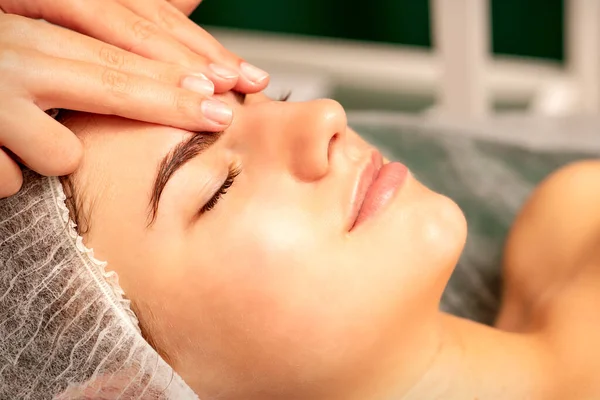 Kafa masajı. Kafkasyalı beyaz güzel bir kadın kaplıca salonundaki kapalı gözlerle kafa ve alın masajı yaptırıyor.