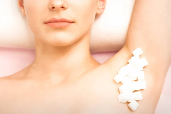 シュアリング ワックスの概念 白い砂糖のキューブは 若い白い女性の女性の脇の下に横たわっている 閉じる — ストック写真