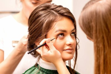 Makeup artist and hairdresser prepare the bride making hairstyle and makeup in a beauty salon