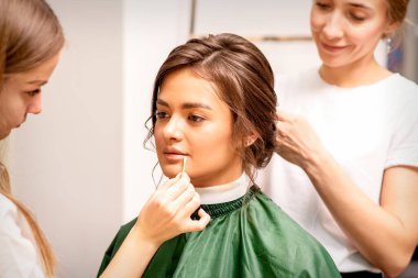 Makeup artist and hairdresser prepare the bride making hairstyle and makeup in a beauty salon