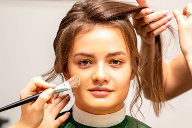 Makeup artist and hairdresser prepare the bride making hairstyle and makeup in a beauty salon