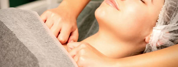 Massaging female breast, and shoulder. Young beautiful caucasian woman with closed eyes receiving chest and shoulders massage in beauty spa salon