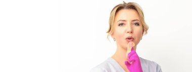Beyaz arka planda pembe eldivenler giyip işaret parmağına balmumu yapıştırıcı süren beyaz bir kadın güzellik uzmanı. Epilasyon kavramı