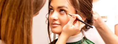 Makeup artist and hairdresser prepare the bride making hairstyle and makeup in a beauty salon