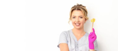 Şekerleme uzmanının elinde sıvı sarı şeker macunu var. Beyaz arka plandaki tahta bir çubukta tüy dökmek için balmumu.