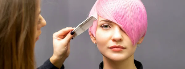 Женщина Парикмахер Расчесывает Окрашенные Розовые Короткие Волосы Молодой Женщины Темной — стоковое фото