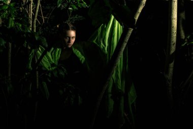 Ağaçlara sarılmış yeşil elbiseli kız.