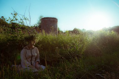 Pagan çelengi içindeki genç kadın otlar içinde