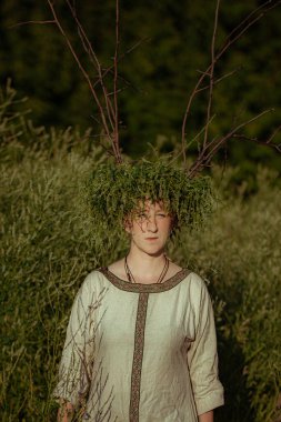 Pagan çelengi içindeki genç kadın otlar içinde