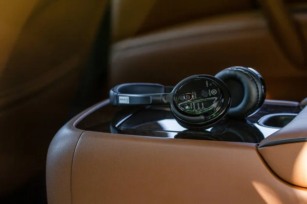 现代无线耳机在现代汽车座椅上 汽车媒体系统用黑色经典耳机的特写 — 图库照片
