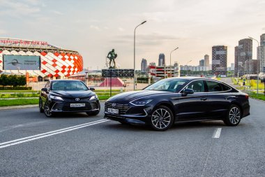 MOSCOW, RUSSIA - AUGust 15, 2021 Hyundai Sonata 8. nesil (DN8) ve Toyota Camry (XV70), orta büyüklükte bir sedan otomobil modeli 2021 yılında şehir arka planında. Dış cephe yakın görünümü.