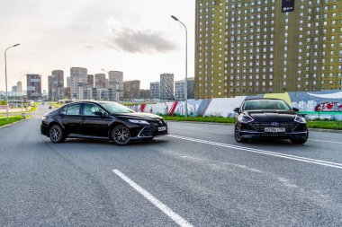 MOSCOW, RUSSIA - AUGust 15, 2021 Hyundai Sonata 8. nesil (DN8) ve Toyota Camry (XV70), orta büyüklükte bir sedan otomobil modeli 2021 yılında şehir arka planında. Dış cephe yakın görünümü.