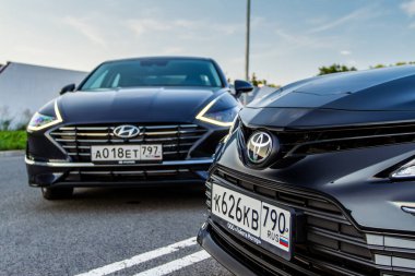 MOSCOW, RUSSIA - AUGust 15, 2021 Hyundai Sonata 8. nesil (DN8) ve Toyota Camry (XV70), orta büyüklükte bir sedan otomobil modeli 2021 yılında şehir arka planında. Dış cephe yakın görünümü.