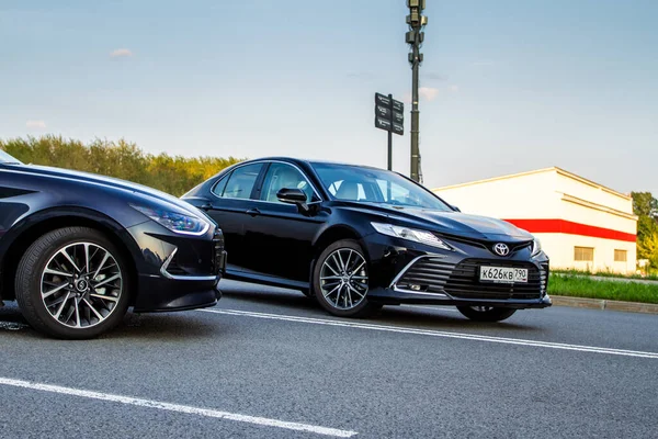 MOSCOW, RUSSIA - AUGust 15, 2021 Hyundai Sonata 8. nesil (DN8) ve Toyota Camry (XV70), orta büyüklükte bir sedan otomobil modeli 2021 yılında şehir arka planında. Dış cephe yakın görünümü.