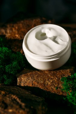 Koyu arkaplanda yeşil yapraklı doğal krema kavanozu.