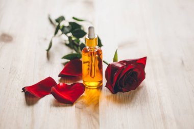 gül yağı ve taze çiçekler ahşap bir arka planda