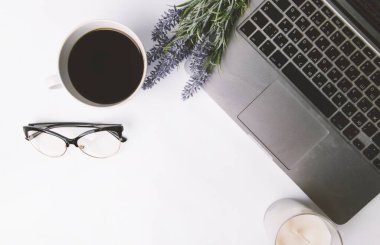 Bilgisayarlı ofis masası, bir fincan kahve ve beyaz arka planda diğer eşyalar. en üstteki görünüm