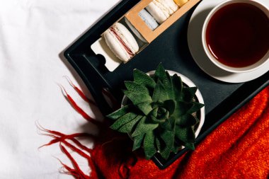 Siyah çay, kırmızı ve beyaz kahve bardağı ve ahşap arka planda peçeteli bir tepsi.