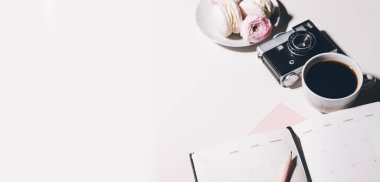 Kahve fincanının ve defterin beyaz ahşap masadaki üst görüntüsü.